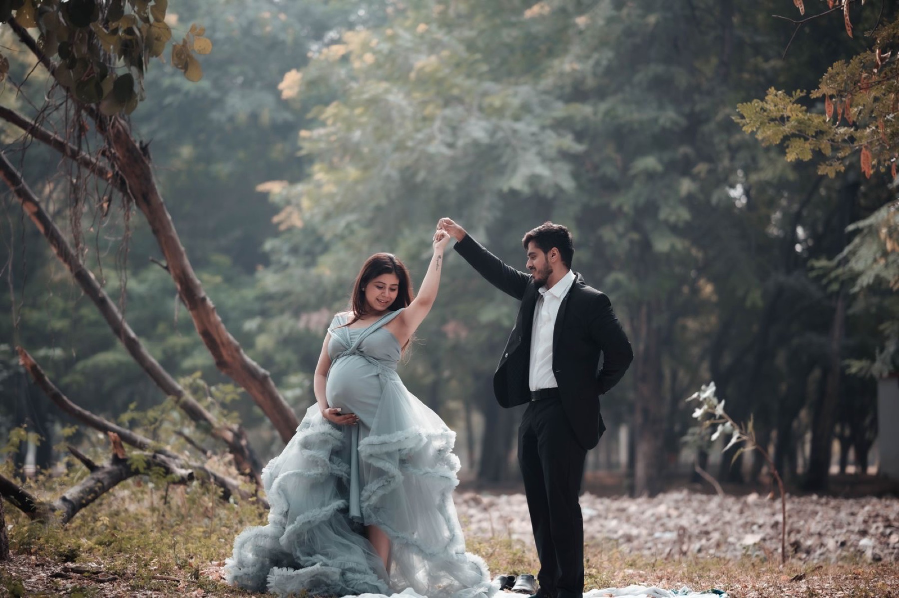 Outdoor blue gown couple maternity photoshoot with natural backdrop